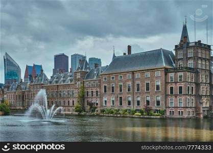 View of the Binnenhof House of Parliament and the Hofvijver lake with downtown skyscrapers in background. The Hague, Netherlands. Hofvijver lake and Binnenhof , The Hague