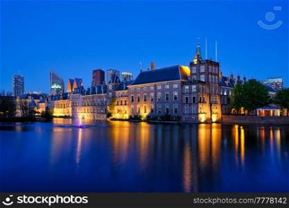 View of the Binnenhof House of Parliament and the Hofvijver lake with downtown skyscrapers in background illuminated in the evening. The Hague, Netherlands. Hofvijver lake and Binnenhof , The Hague
