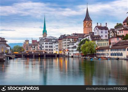 View of the city embankment and the clock tower at sunset. Zurich. Switzerland.. Zurich. View of the city embankment and the facades of old houses.