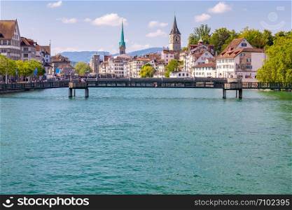 View of the city embankment bridges and the clock tower in the early morning. Zurich. Switzerland.. Zurich. View of the city embankment and the facades of old houses.