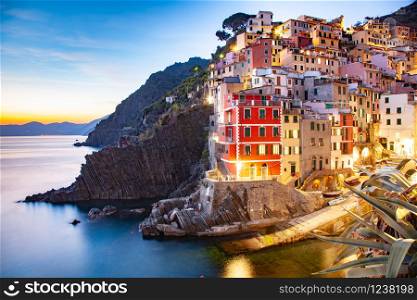 view of the colorful houses at night along the coastline of Cinque Terre area in Riomaggiore, Italy