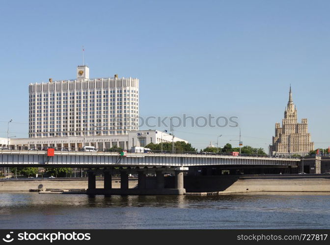 View of the Government House (White House) of the Russian Federation in Moscow. Novoarbat Bridge across the Moskva River (Moscow River). Summer day, blue sky.