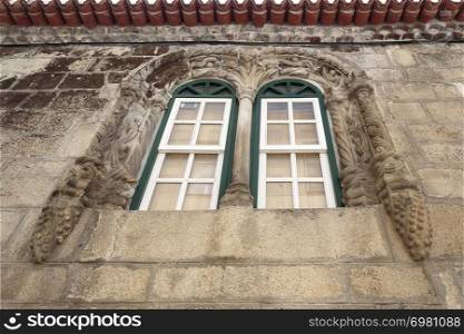 View of the Manueline window of the Tower House with three archivolts of strings finishing the first in an inverted pine cone, in Gouveia, Beira Alta, Portugal