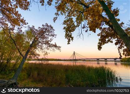 View of the Moskovsky bridge over the Dnieper river at dusk in autumn, in Kiev, Ukraine
