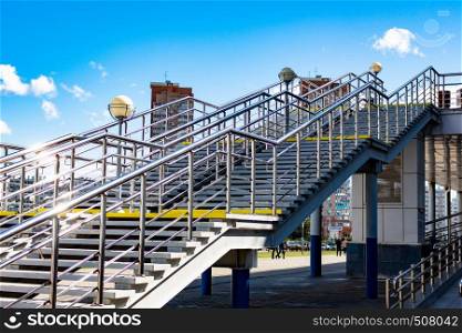 View of the new modern houses of the city of Khabarovsk. Bright blue sky on a Sunny day. Diagonal shiny railing in the foreground.. Khabarovsk, Russia - Sep, 09, 2019: View of the coastal district from the hockey arena Erofey in bright Sunny weather. Bright blue sky on a Sunny day. Diagonal shiny railing in the foreground.