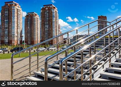 View of the new modern houses of the city of Khabarovsk. Bright blue sky on a Sunny day. Diagonal shiny railing in the foreground.. Khabarovsk, Russia - Sep, 09, 2019: View of the coastal district from the hockey arena Erofey in bright Sunny weather. Bright blue sky on a Sunny day. Diagonal shiny railing in the foreground.