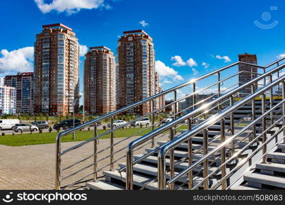 View of the new modern houses of the city of Khabarovsk. Bright blue sky on a Sunny day. Diagonal shiny railing in the foreground.. Khabarovsk, Russia - Sep, 09, 2019: View of the coastal district from the hockey arena Erofey in bright Sunny weather. Bright blue sky on a Sunny day. Diagonal shiny railing in the foreground.