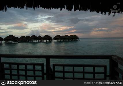 View of the ocean with thatched structures on stilts, Moorea, Tahiti, French Polynesia, South Pacific