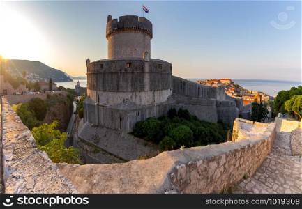 View of the old medieval stone city walls and and lighthouse at dawn. Dubrovnik. Croatia.. Dubrovnik. Old city walls and towers in the early morning.