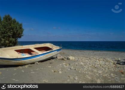View of the pebble beach of Maleme with a boat . View of the pebble beach of Maleme with a boat abandon in the north west of the island of Crete in Greece