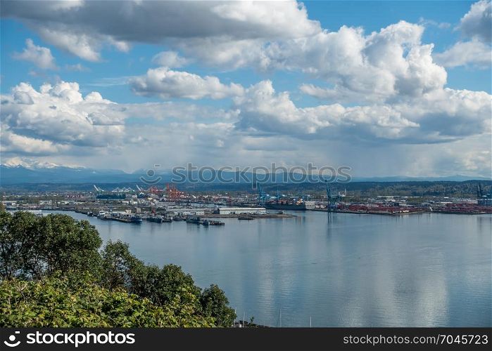 View of the Port Of Tacoma on a sunny day. Puffy clouds are reflected in the calm waters of the Puget Sound.