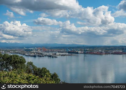 View of the Port Of Tacoma on a sunny day. Puffy clouds are reflected in the calm waters of the Puget Sound.