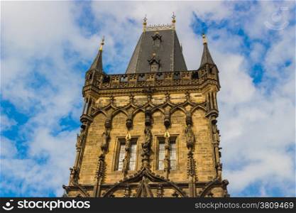 View of the Powder Tower in Prague: dark and gothic tower on cloudy blue sky