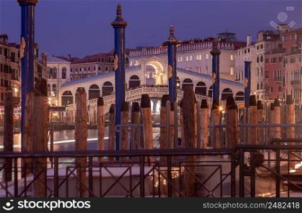 View of the Rialto Bridge and Grand Canal in a night lighthouse at sunset. Venice. Italy.. Venice. Old medieval Rialto bridge in night illumination.