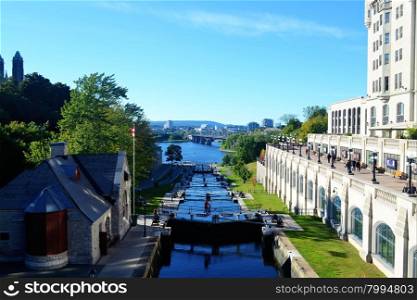 View of the rideau canal in Ottawa, Canada, with the locks open anda hotel on the right side, in bright sunshine.