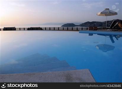 View of the swimming pool and the sea and sky in the background on Crete island in Greece at sunrise.