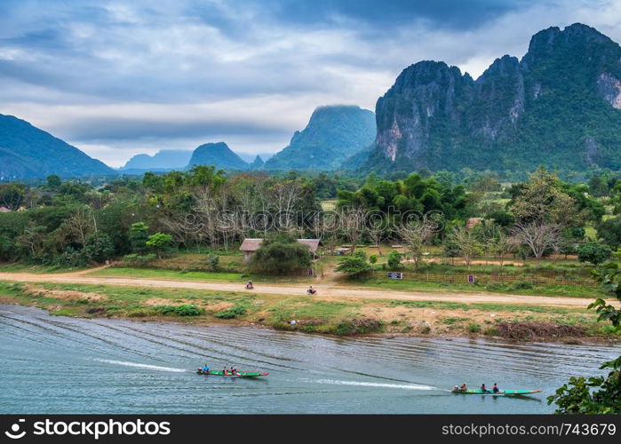 View of the tourist boats on the Nam Song River and mountains background in Vang Vieng, Laos.