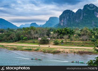View of the tourist boats on the Nam Song River and mountains background in Vang Vieng, Laos.