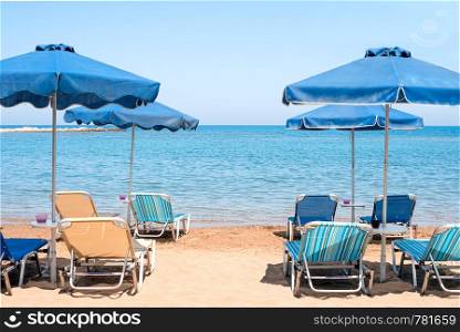 View of the transparent blue sea from coast with bright blue umbrellas. View of the transparent blue sea from coast with blue umbrellas