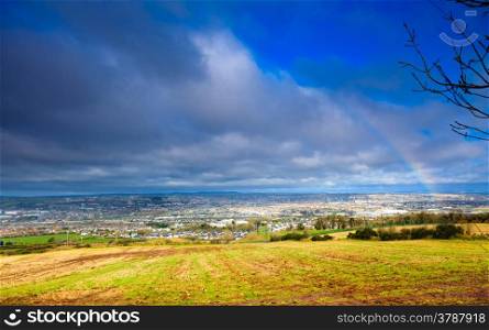View of town Cork, County Cork, Ireland Europe. Cloudscape with colorful rainbow over autumn city, beautiful colors phenomenon in blue sky, overcast weather, nature landscape