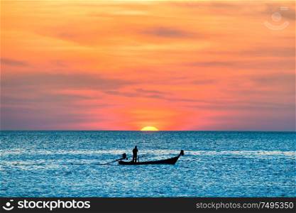View of traditional fishing boat in blue sea during beautiful orange sunset