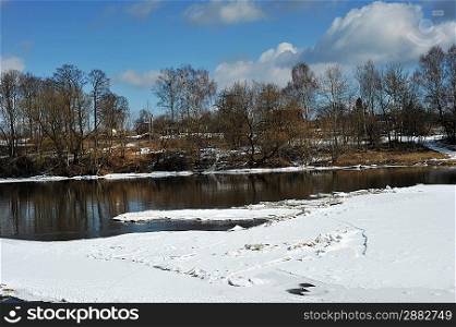 View of trees, snow, ice and river on winter day