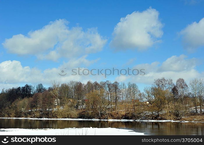 View of trees, snow, ice and river on winter day