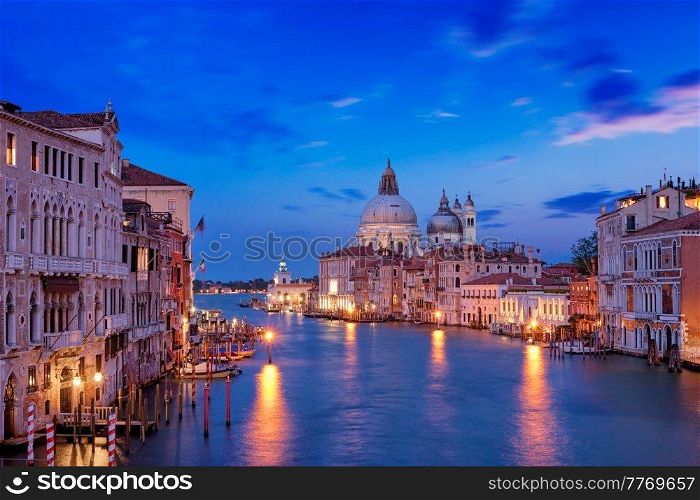 View of Venice Grand Canal with boats and Santa Maria della Salute church in the evening from Ponte dell’Accademia bridge. Venice, Italy. View of Venice Grand Canal and Santa Maria della Salute church in the evening
