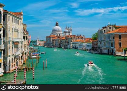 View of Venice Grand Canal with boats and Santa Maria della Salute church in the day from Ponte dell’Accademia bridge. Venice, Italy. View of Venice Grand Canal and Santa Maria della Salute church on sunset