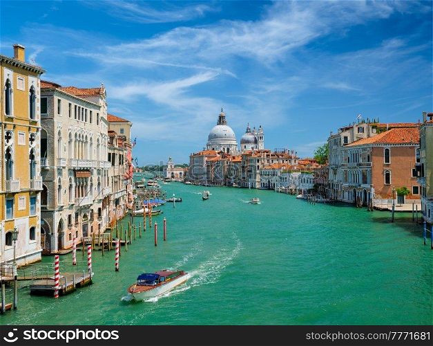 View of Venice Grand Canal with boats and Santa Maria della Salute church in the day from Ponte dell’Accademia bridge. Venice, Italy. View of Venice Grand Canal and Santa Maria della Salute church on sunset