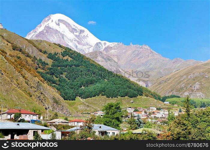 view of village Stepantsminda, Gergeti Trinity Church and Mount Kazbek in Caucasus Mountains in Georgia