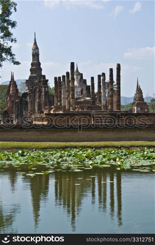 view of Wat Mahathat behind a lake in Sukhothai