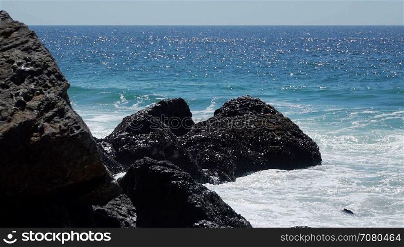 View of waves hitting rocks on a sunny day at Point Dume