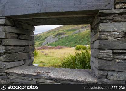 View of Welsh hillside with slate quarry through derelict window frame.