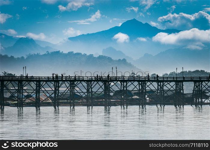 View of Wooden bridge over the river with beautiful mountains in the background. Beautiful sky mountains and MON BRIDGE at Thailand