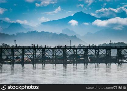 View of Wooden bridge over the river with beautiful mountains in the background. Beautiful sky mountains and MON BRIDGE at Thailand
