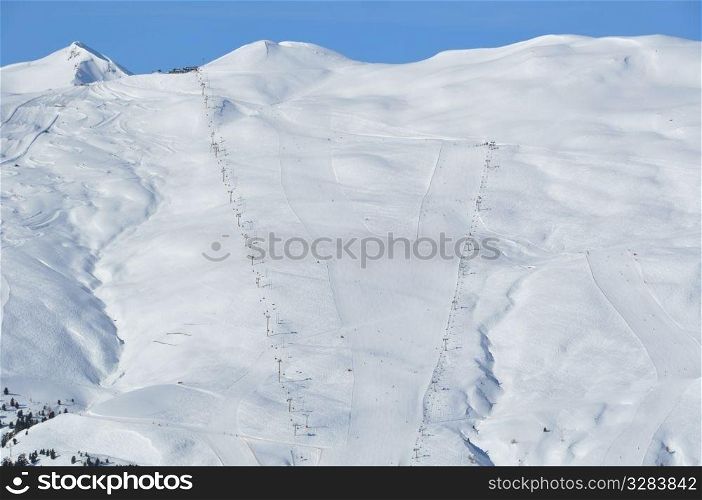 View on a steep skking mountain with two slopes, skiers and lifts - shot in Livigno, Italian Alps