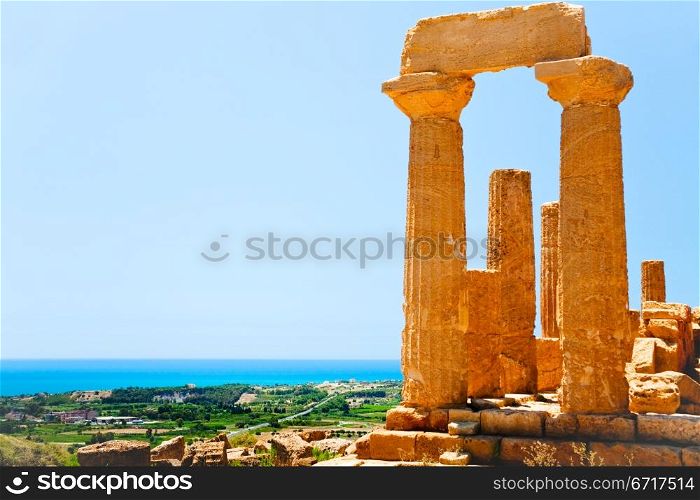 view on Dorian columns of Temple of Juno and sea coast in Valley of the Temples in Agrigento, Sicily