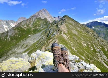 view on hiking shoes wearing by a woman sitting in mountain in beautiful landscape