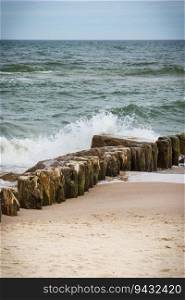 View on landscape of beach and wooden breakwaters with sea waves. Stormy and windy day at sea. Landscape of beach and wooden breakwaters with sea waves. Stormy day at sea