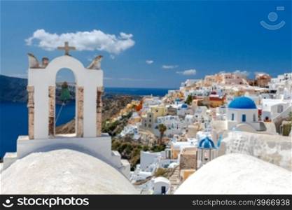 View on Oia village with traditional blue and white houses.. Church bell tower in Oia on Santorini Island.