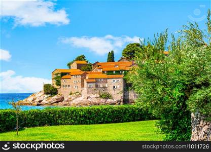 View on Sveti Stefan from a green meadow at sunny summer day, Montenegro. View on Sveti Stefan