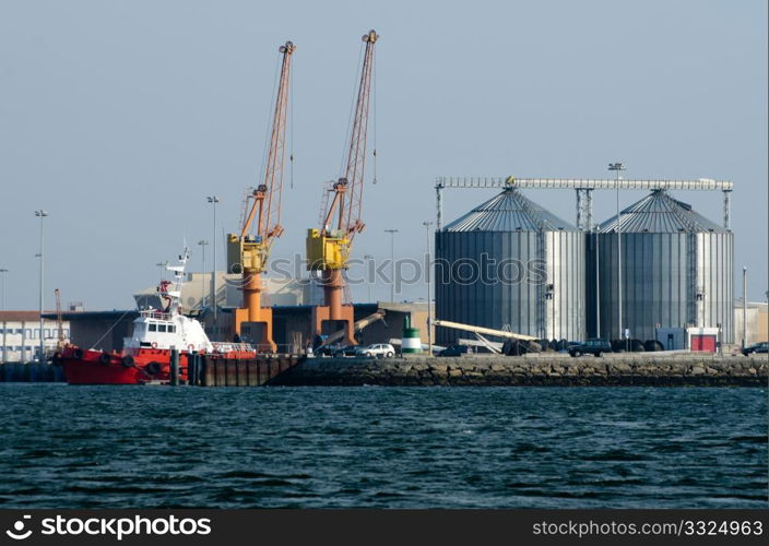 View on trading seaport with cranes and red tug boat.