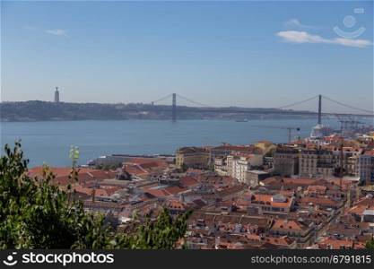 view on travel city Lisbon from top place of castle sao jorge. roofs, river tejo, brige 25 april, ships in summer day.