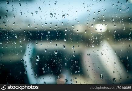 View on wet street at rainy day through window with water drops