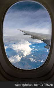 view out the window of an aircraft wing and the Brazilian landscape through clouds