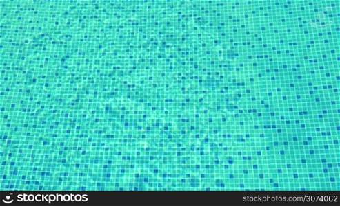 View the the clear rippling water in blue tiled swimming pool on sunny summer day. Vacation and recreation