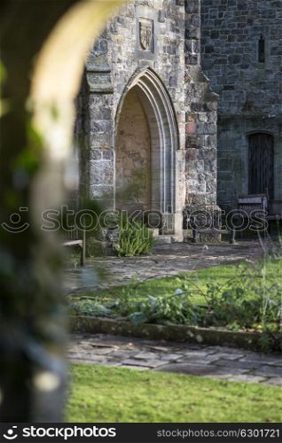 View through stone archway into medieval landscape garden with shallow depth of field for focus where required
