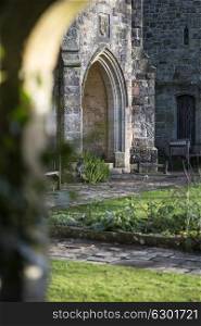 View through stone archway into medieval landscape garden with shallow depth of field for focus where required