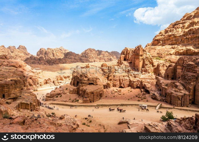 View to the ancient Nabataean Royal tombs and main street of Petra full of tourist, Jordan